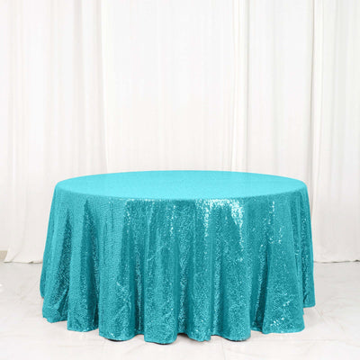 Turquoise sequin tablecloth on a round table against a white background