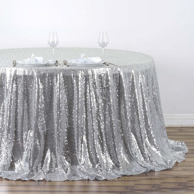 Silver sequin tablecloth draped elegantly on a round table with glassware.