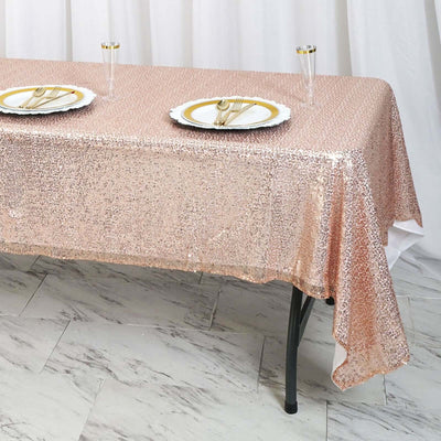Rose gold sequin tablecloth draped over a table set with plates and glasses.