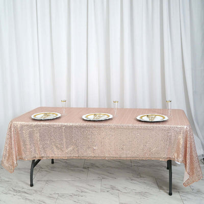 Rose gold sequin tablecloth draped over a table with plates and glasses set.