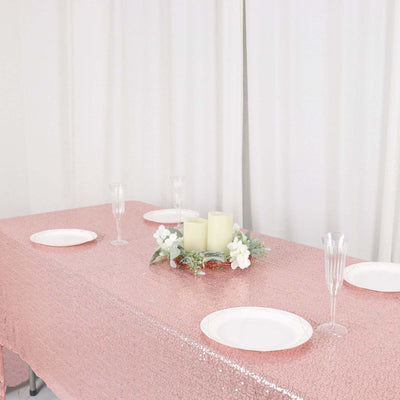 Elegant pink sequin tablecloth with candles and plates for a festive table setting.