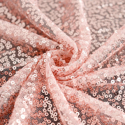 Pink sequin fabric in a swirling pattern for crafting and design projects.
