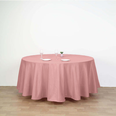 Round pink tablecloth draped over a table with plates and glasses