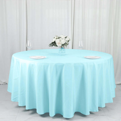Round turquoise tablecloth on a dining table with floral centerpiece.