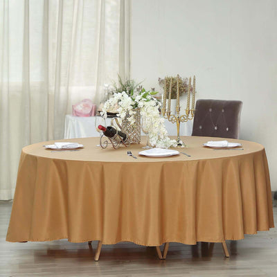 Round gold tablecloth on a dining table set with plates and decor.