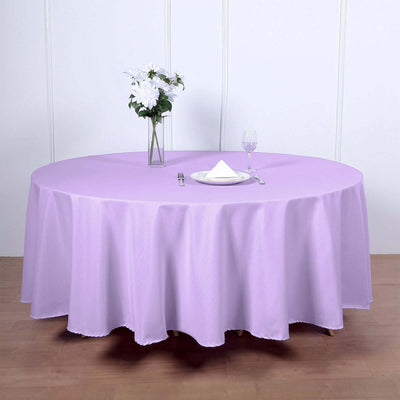 Round lavender tablecloth draped over a table with a floral centerpiece and glassware.