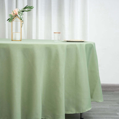 Green tablecloth draped over a table with a glass and floral centerpiece.