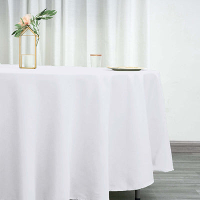 Elegant white tablecloth draping over a table with vase and glass.