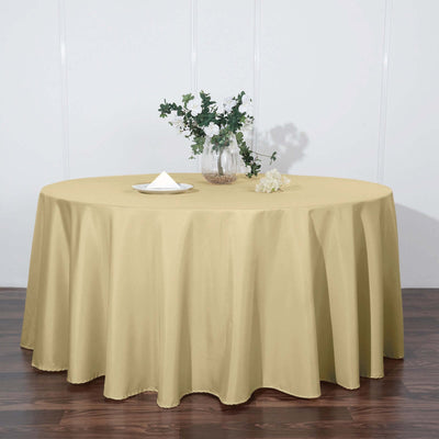 Round gold tablecloth draped over a table with floral arrangement.