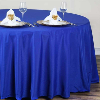 Round blue tablecloth draped over a table set with elegant dinnerware.