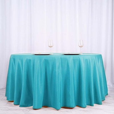 Turquoise tablecloth draped over a round table with wine glasses.