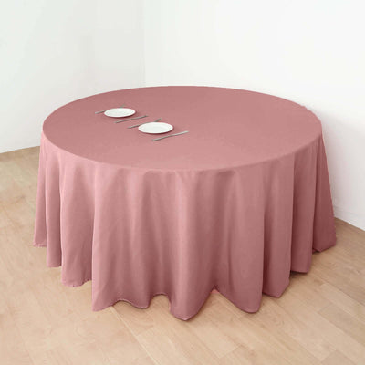 Round table with pink tablecloth and two plates, set in a minimalistic dining space.