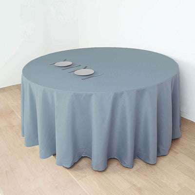Round gray tablecloth draped over a table with three plates on top.