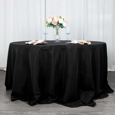 Elegant black tablecloth set for dining with floral centerpiece and glassware.