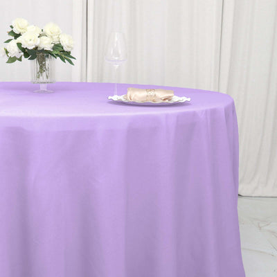 Lavender tablecloth draped over a round table with a floral centerpiece and glassware.