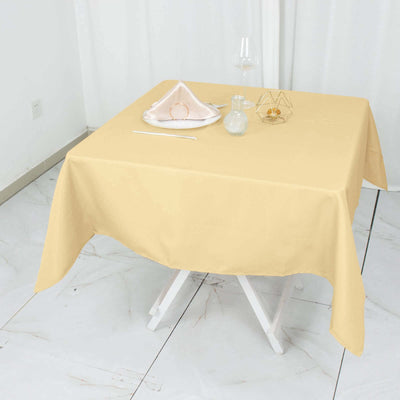 Yellow tablecloth on a dining table set with decor and glassware.