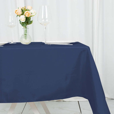 Navy blue tablecloth on a dining table with glasses and a vase of flowers
