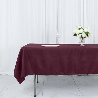 Burgundy tablecloth draped over a table with a decorative vase and wine glass.