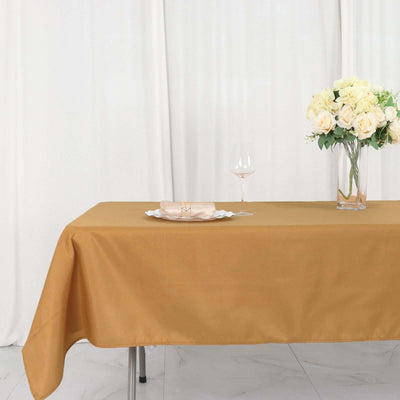 Elegant mustard yellow tablecloth with floral centerpiece and glass on a dining table.