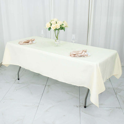 Elegant cream tablecloth draped over a table with floral centerpiece and tableware.