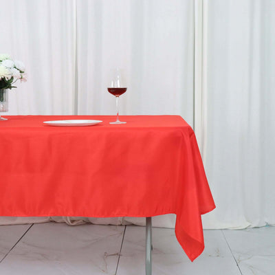 Red tablecloth draped over a table with a glass of wine and a plate