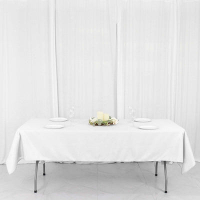 White table set with plates and floral centerpiece on a plain backdrop
