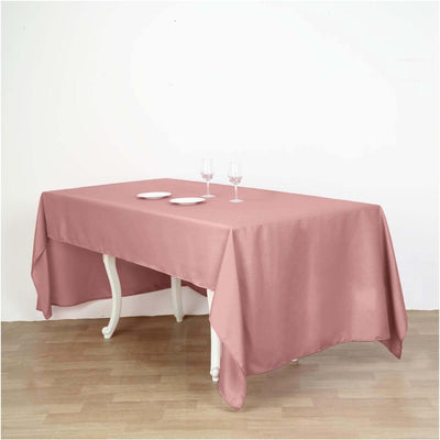 Pink tablecloth draped over a wooden table set with glasses and plates.