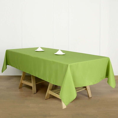 Green tablecloth on a wooden table with white plates.