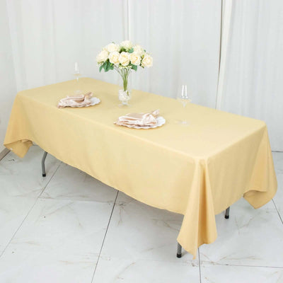 Yellow tablecloth draped elegantly over a table set with flowers and dinnerware.