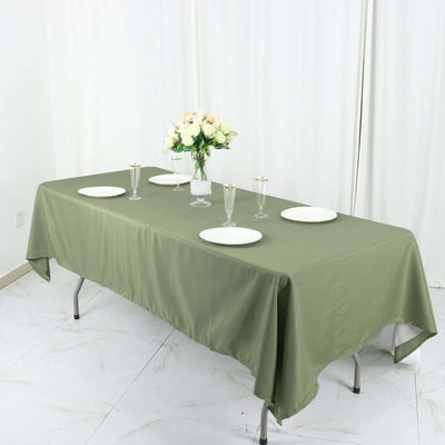 Green tablecloth draped over a table set with plates and floral centerpiece.