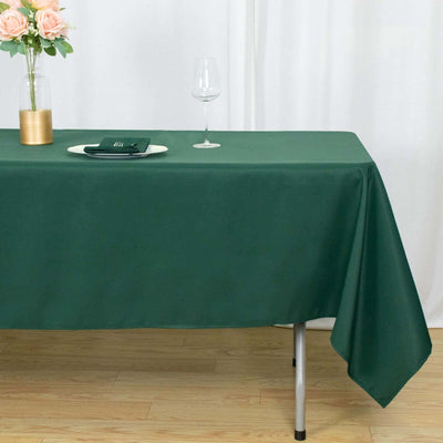 Green tablecloth draped elegantly on a table with a vase and glass.