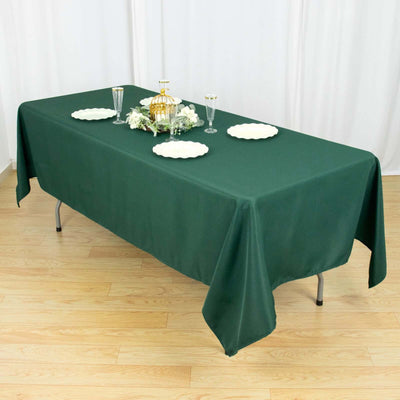 Green tablecloth draped over a table set for an elegant dinner.