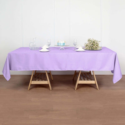Lavender tablecloth on a wooden table set for dining with glassware and decor.