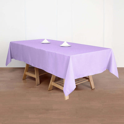 Purple tablecloth on a wooden table with white decor items.