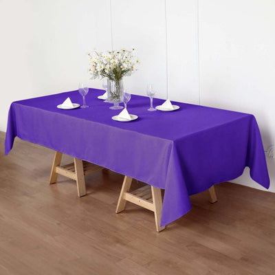Purple tablecloth draped over a wooden table set for dining.