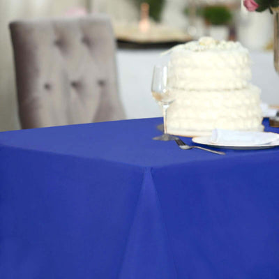 Blue tablecloth on a dining table set for a celebration with a cake.