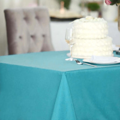 Teal tablecloth elegantly draped on a table with a wedding cake and glassware.