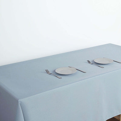 Gray tablecloth with plates and cutlery set on a simple table.