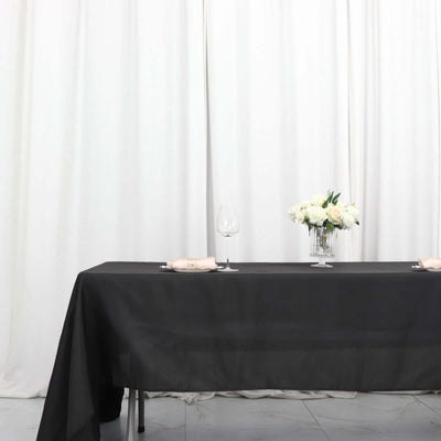 Elegant black tablecloth set for dining with flowers and glassware.