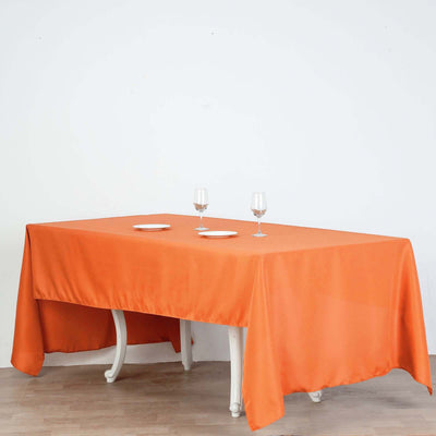 Orange tablecloth draped over a table with wine glasses and plates