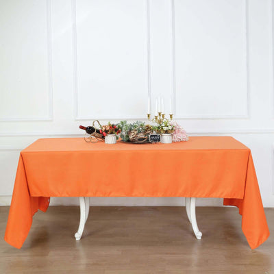 Orange tablecloth draped over a table with decorative items on top.