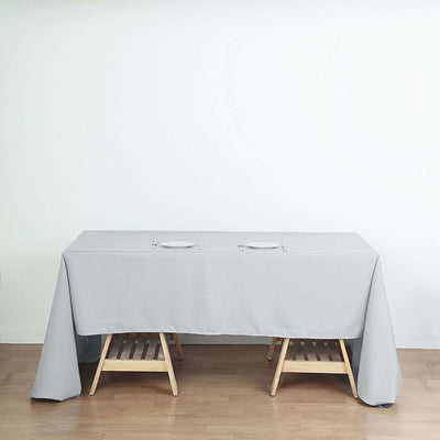 Gray tablecloth draped over a wooden table with cutouts for plates.