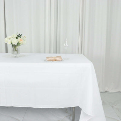 Elegant table setting with white tablecloth, napkin, glass, and floral arrangement.