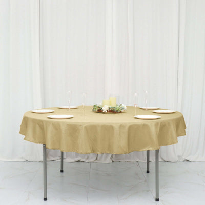 Round gold tablecloth on a dining table with plates and decorative centerpieces.