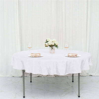 Elegant round table set with a white tablecloth, plates, and a floral centerpiece.