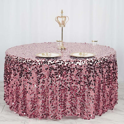 Pink sequin tablecloth with crown centerpiece and elegant plates.