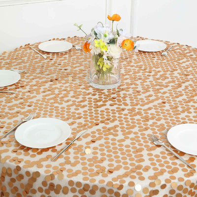 Round table with gold sequin tablecloth and floral centerpiece.
