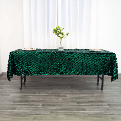 Green sequin tablecloth on a table with flowers in a vase.