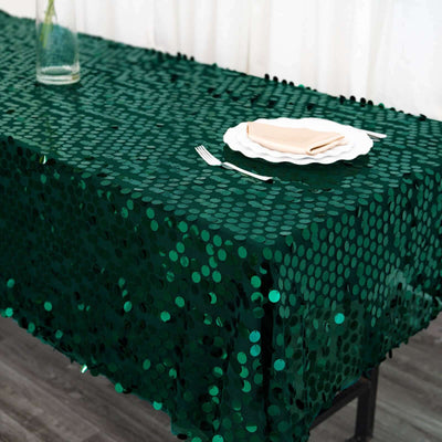 Green sequin tablecloth on a dining table with plates and cutlery.