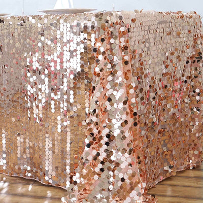 Rose gold sequin tablecloth draping elegantly over a wooden table.